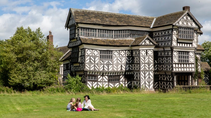 A family having a picnic on the lawn at Little Moreton Hall, Cheshire
